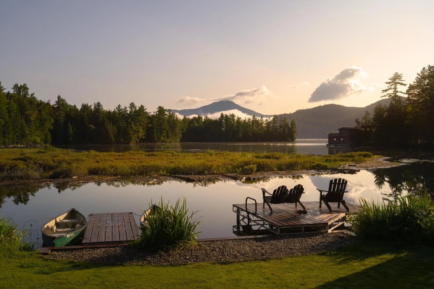 A lake with a dock and chairs on it.