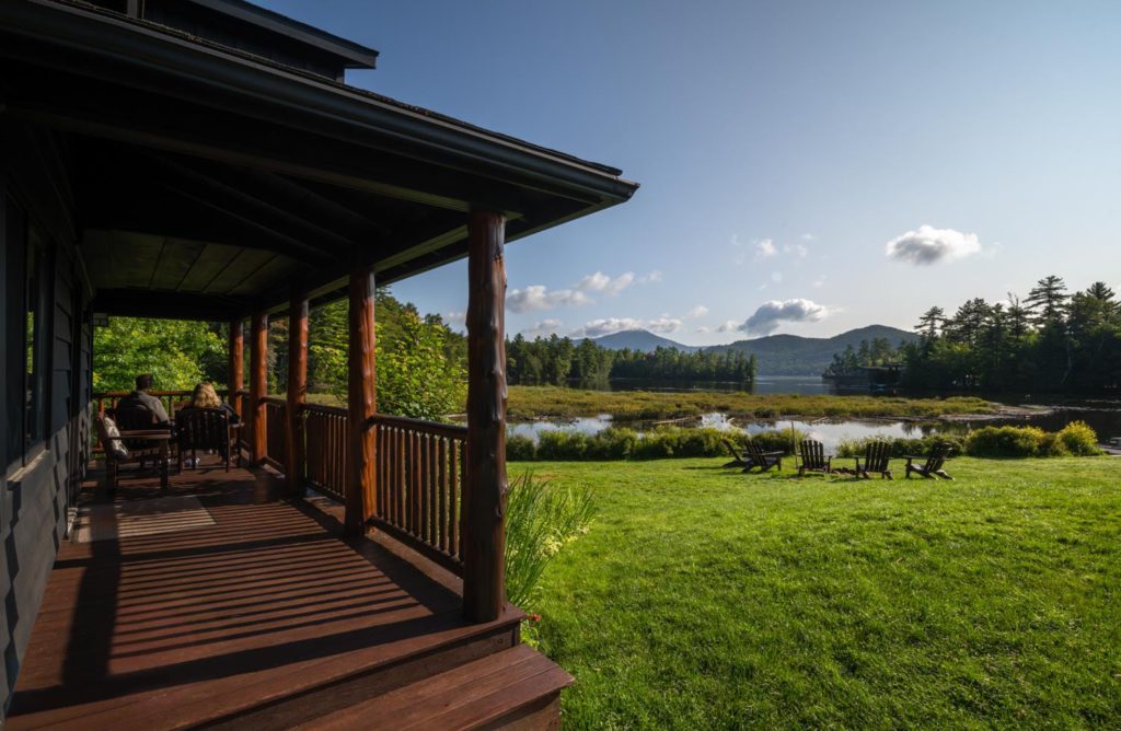The porch of a cabin overlooking a lake.