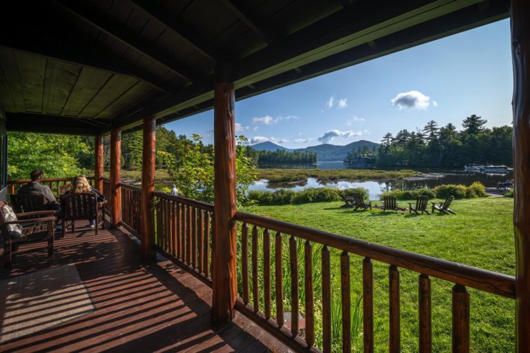 A porch overlooking a lake and mountains.
