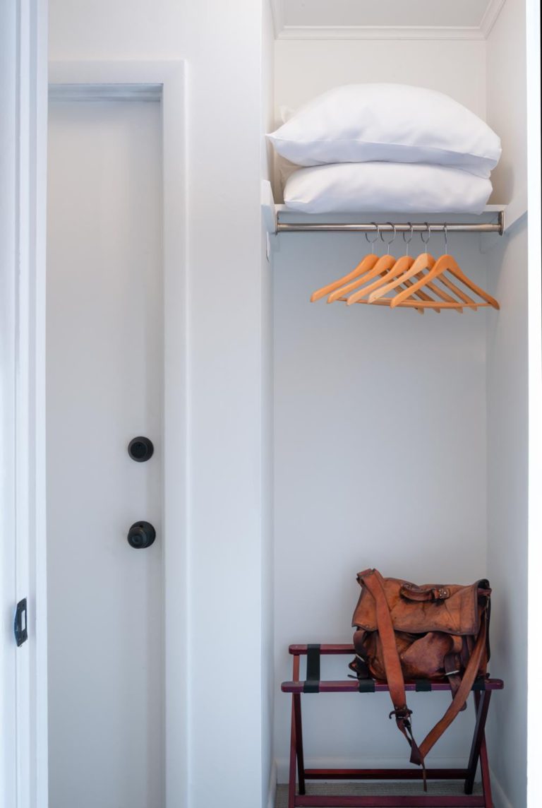 A closet with hanging clothes and a bench.
