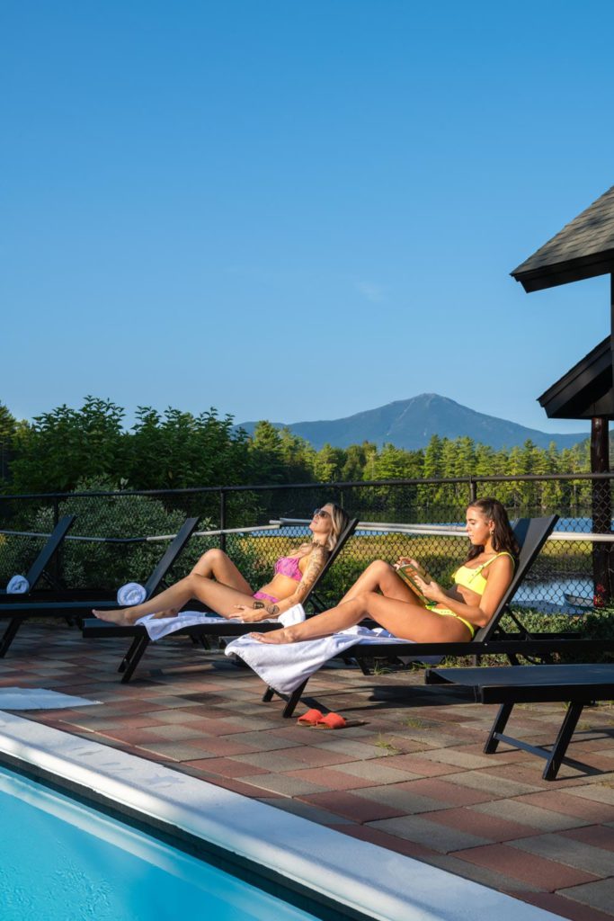 Two women relaxing in lounge chairs near a swimming pool.