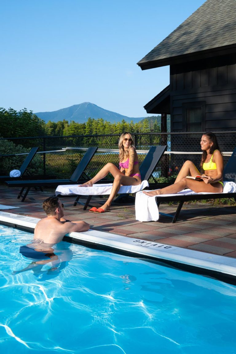 A group of people relaxing in a pool next to a lodge.