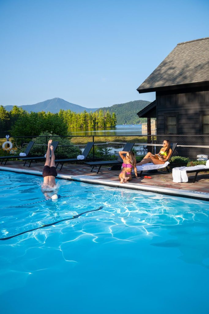 A group of people swimming in a pool near a cabin.