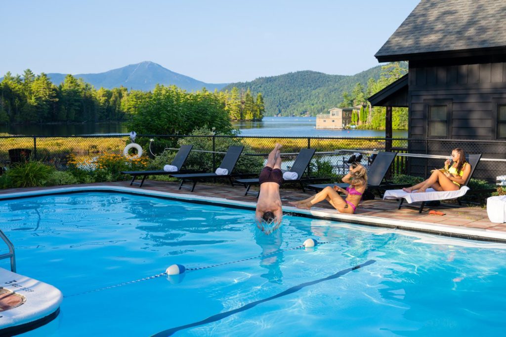 A group of people swimming in a pool near a cabin.