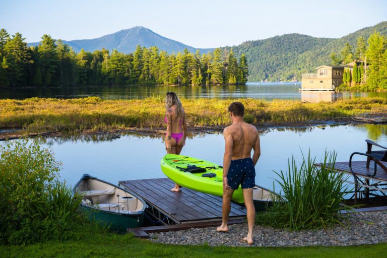 Two people standing on a dock with a kayak.