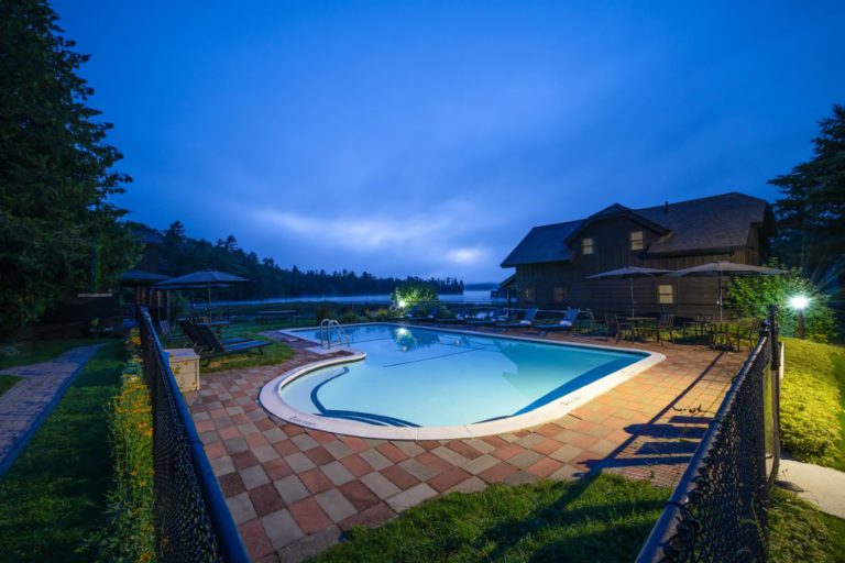 A swimming pool in front of a house at night.