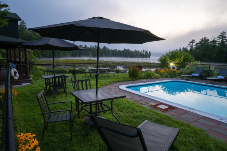 A pool with chairs and umbrellas next to a lake.