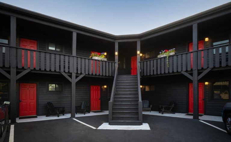 A black motel with red doors and stairs.