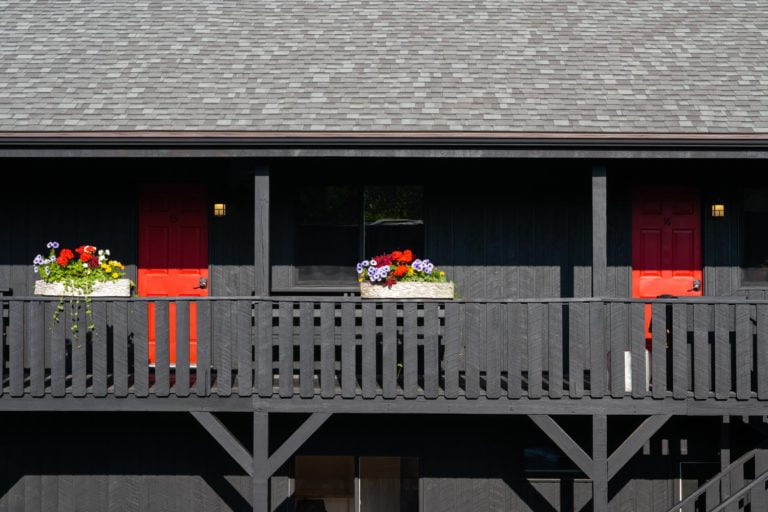 A black building with red flower boxes on the balcony.