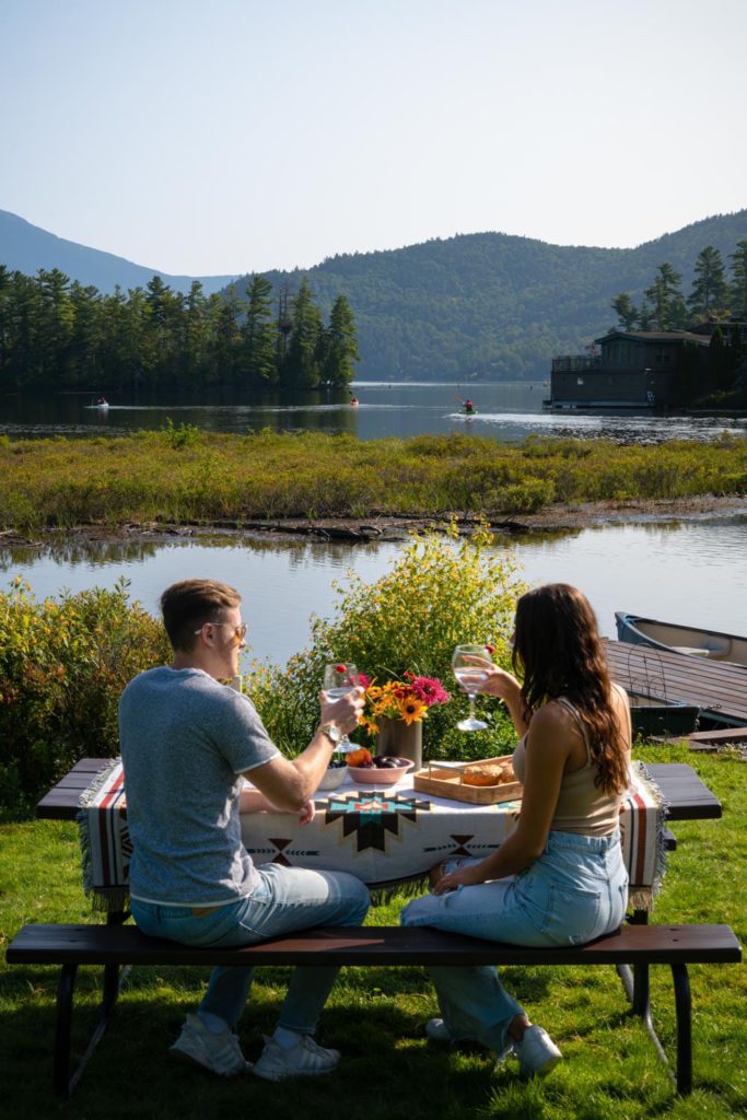 Two people sitting at a picnic table near a lake.