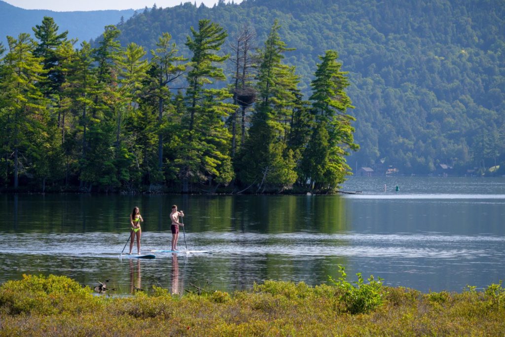 Two people stand up paddle boarding on a lake.