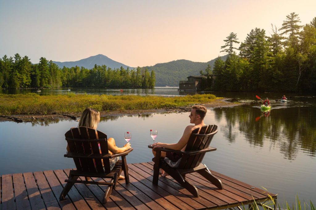 Two people sitting on a dock overlooking a lake.
