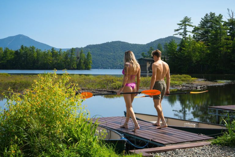Two people standing on a dock near a lake.