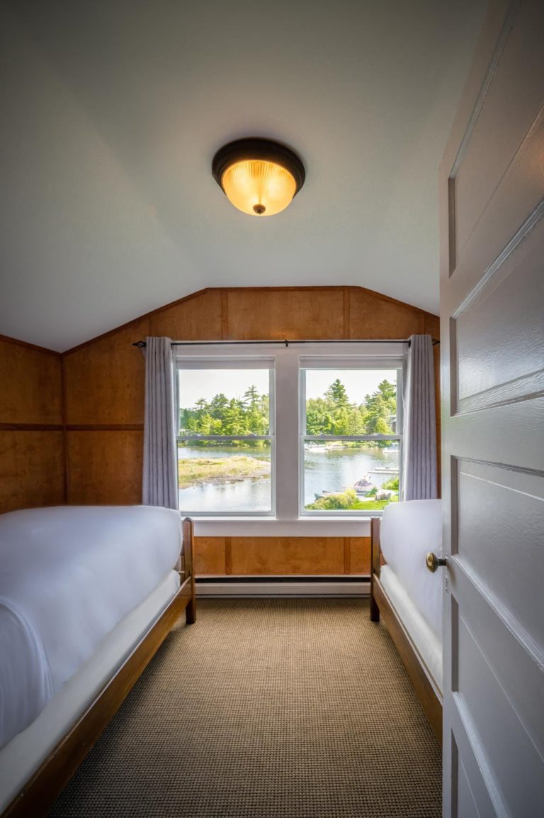 Two beds in a room with a view of the water.