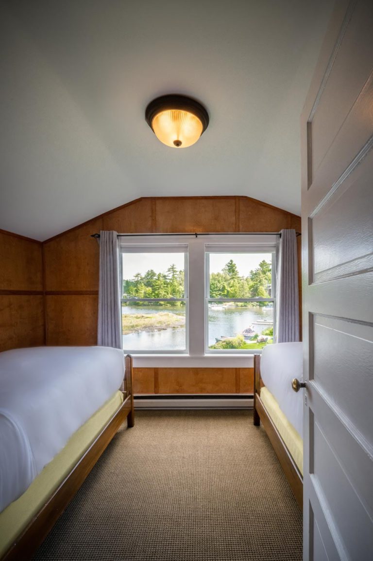 Two beds in a room with a view of the water.