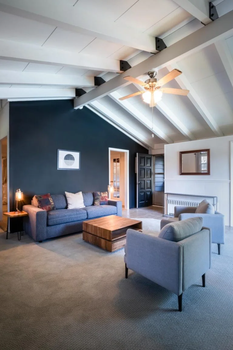 A living room with blue couches and a ceiling fan.