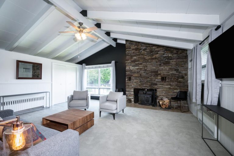A living room with a stone fireplace and a flat screen tv.