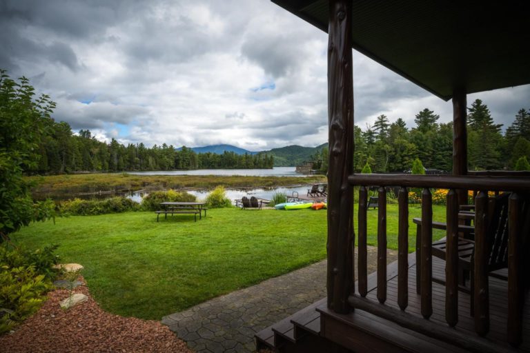 A view from the porch of a cabin overlooking a lake.