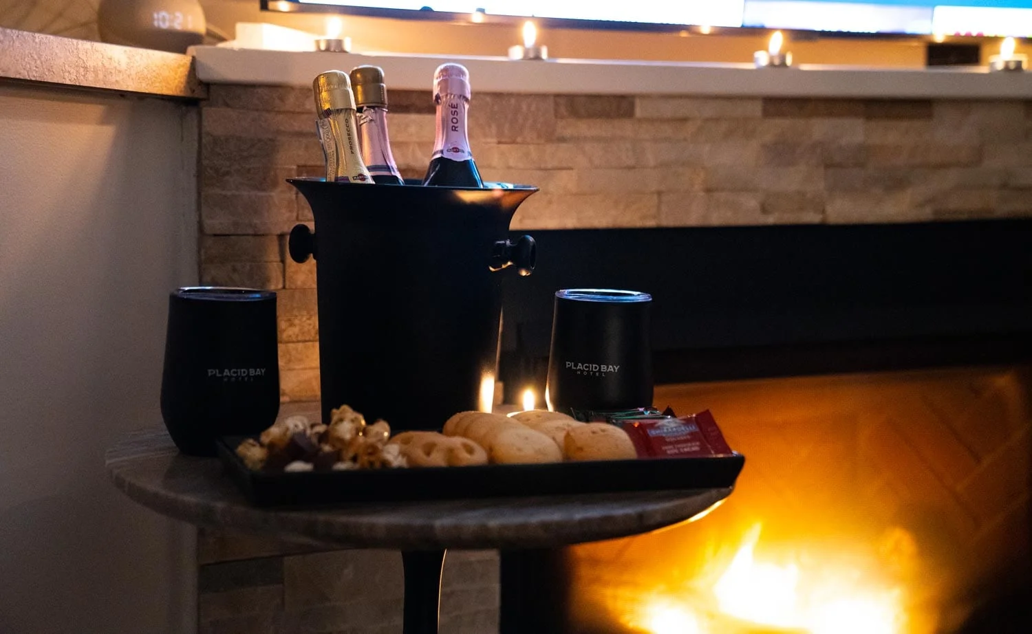 A bottle of champagne sits on a table next to a fireplace.
