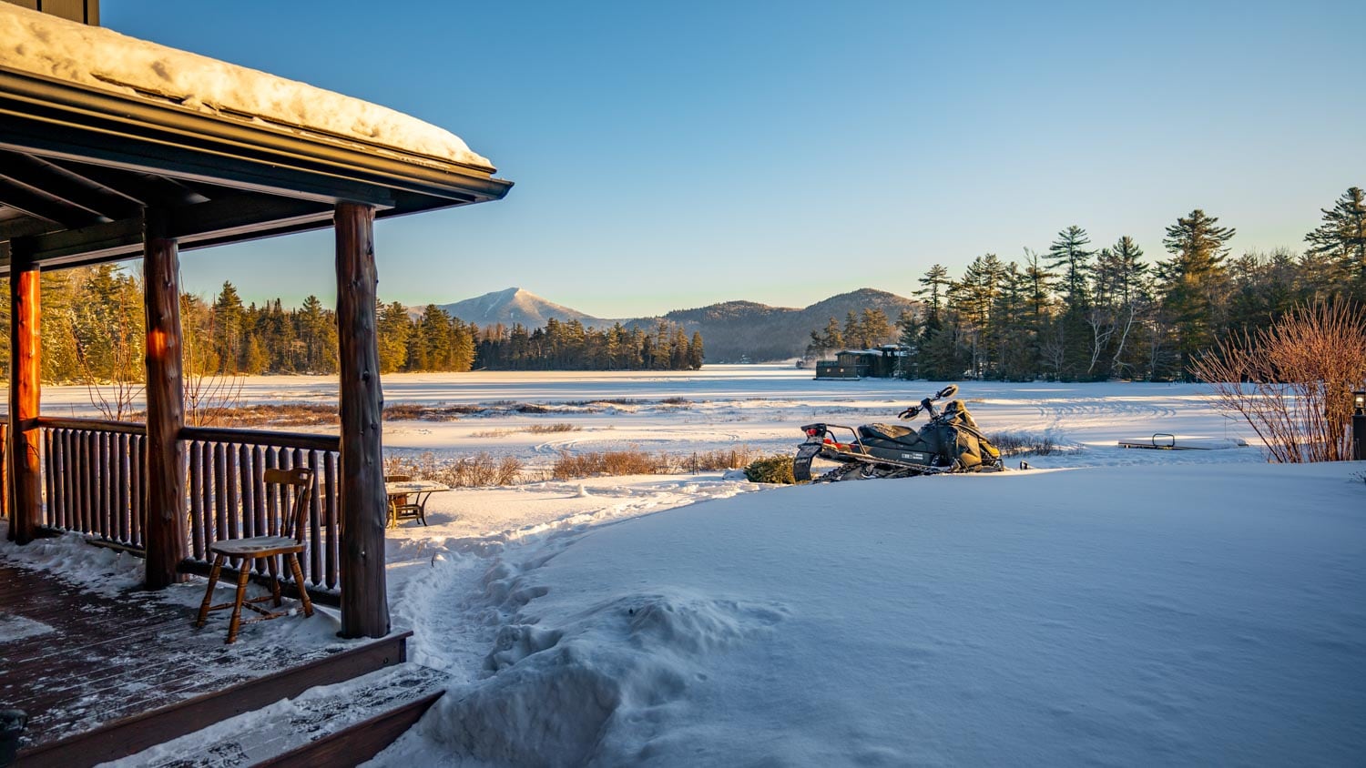 A snow covered porch with a view of a lake.